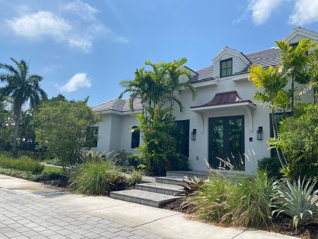 White two-story residence with palms, ornamental grasses and paver walk